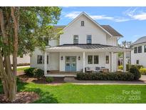 Charming white home featuring a welcoming front porch with a swing and vibrant blue double doors at 309 Catawba Ave, Davidson, NC 28036