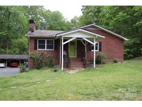 Charming brick home featuring a covered front porch, well-maintained lawn, and mature trees offering a warm, inviting curb appeal at 347 Poole Rd, Troy, NC 27371