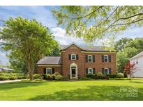 Traditional brick home with manicured lawn, mature landscaping, and black shutters on a sunny day at 4611 Cringle Ct, Charlotte, NC 28226