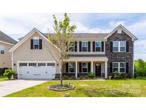 Two story home features a blend of vinyl siding and stone facade with neat landscaping at 7412 Greene Mill Sw Ave, Concord, NC 28025