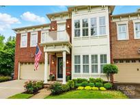 Beautiful brick home featuring an American flag, a two-car garage, manicured landscaping, and a charming front porch at 9652 Wheatfield Rd, Charlotte, NC 28277