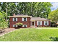Charming brick home featuring white shutters and a well-manicured lawn with mature trees at 1024 Regency Dr, Charlotte, NC 28211