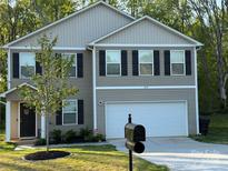 Charming two-story home features a two-car garage, complemented by a landscaped front yard and dark shutters at 1070 Glenbriar Ct, Woodleaf, NC 27054