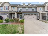 Charming townhome featuring a two-car garage, stone accents, a well-manicured lawn and inviting curb appeal at 11062 Discovery Nw Dr, Concord, NC 28027