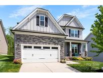 Beautiful two-story home featuring stone accents, a two-car garage, and a welcoming front porch with rocking chairs at 2936 Shumard Dr, Gastonia, NC 28054