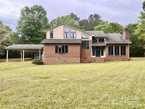 Spacious back exterior view of brick home with a carport and lush green lawn and mature trees at 611 Stowe Rd, Clover, SC 29710