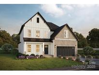 Charming two-story home featuring light siding, stone accents, a dark roof, a two car garage, and manicured landscaping at Lot 1 Henderson Cir, Harrisburg, NC 28075