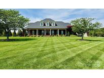 Expansive front yard with manicured lawn leads to a beautiful brick home with a covered front porch at 107 Cedar Lake Dr, Statesville, NC 28625