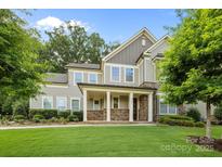 Beautiful two-story home featuring a manicured lawn, stone accents, a covered porch, and lush landscaping at 11304 Preservation Ln, Charlotte, NC 28278