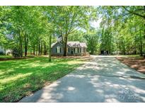 Charming single-story home with mature trees, a manicured lawn, and a long driveway at 1522 Stafford Ext, Monroe, NC 28110