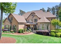 Stunning home featuring a stone and stucco facade, mature landscaping, and a welcoming front porch at 202 Timber Lake Dr, Troutman, NC 28166