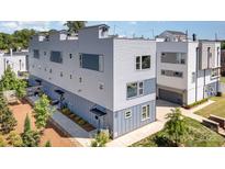 Modern townhome showcasing a sleek design with a mix of gray and blue siding with manicured landscaping at 302 Wesley Heights Way, Charlotte, NC 28208