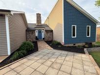Charming home featuring a stone chimney, a blue front door, and a paved entrance area at 5050 Forest Ridge Dr, Hickory, NC 28602