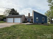 Charming home with a blue facade, stone chimney, and a two-car garage at 5050 Forest Ridge Dr, Hickory, NC 28602