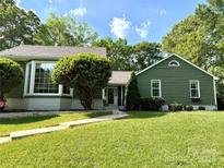 Charming home featuring a lush green lawn, mature trees, and beautiful exterior details at 5916 Rexwood Pl, Charlotte, NC 28210