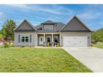 Charming one-story home boasts a manicured lawn, inviting front porch, attached two-car garage, and neutral siding at 604 Airport Rd, Kannapolis, NC 28081