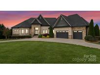 Beautiful stone and brick home with an attached three-car garage and a well-manicured lawn at 767 Pinnacle Dr, Iron Station, NC 28080