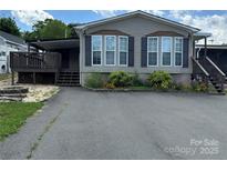 Charming home featuring well-maintained landscaping, flowerbeds, dark shutters, and a covered porch on a sunny day at 116 Dove Ln, New London, NC 28127