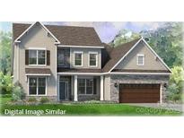 Charming two-story home featuring stone accents, attached garage, and manicured lawn at 128 Adalyn Ivy Ln # 5, Mooresville, NC 28115