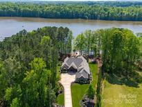 Stunning aerial view of a luxury waterfront home with lush landscaping and private dock at 1579 Sunset Pointe Dr, Salisbury, NC 28146
