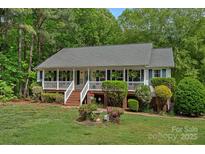 Charming single-story home with a welcoming front porch, manicured lawn, and mature landscaping at 160 Kingfisher Dr, Mooresville, NC 28117