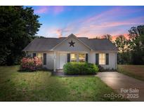 Charming single-story home with well-maintained lawn and landscaping, including flowering shrubs, under a colorful dusk sky at 244 Whitesides Rd, Bessemer City, NC 28016