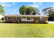 Charming brick home featuring a well-manicured lawn, blue shutters, and a welcoming front porch at 300 Scotland Dr, Kings Mountain, NC 28086