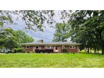 Charming brick ranch-style home with a well-manicured lawn and mature trees at 6615 Mount Holly Rd, Charlotte, NC 28214