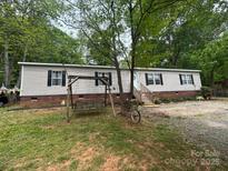 Charming single-story home with a swing and lush greenery surrounding the property at 103 Riding Rd, Mount Holly, NC 28120