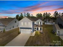 Charming two-story home featuring blue and white siding, a two-car garage, and a manicured front yard at 2022 Mcdonald Dr, Stanfield, NC 28163