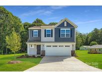 Charming two-story home featuring a two-car garage, well-manicured lawn, and a combination of gray and blue siding at 2106 Columbidae Ln, Gastonia, NC 28052