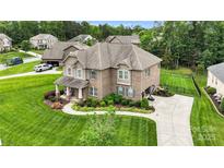 Beautiful brick home with manicured lawn and landscaping, featuring a long driveway and mature trees at 2655 Stonewood Vw, Kannapolis, NC 28081