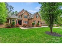 Inviting two-story brick home featuring a lush lawn and manicured landscaping at 8032 Turnberry Ln, Stanley, NC 28164