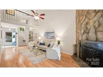 Bright living room with stone fireplace, neutral decor, and hardwood floors in modern home at 8326 Ramath Dr, Charlotte, NC 28211