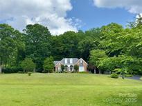 Charming brick home with dormers nestled amongst mature trees and expansive front yard at 15546 Thompson Rd, Mint Hill, NC 28227