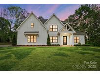 Two-story white farmhouse-style home with modern black trim, a covered porch and manicured lawn at 6712 Cove Ln, Sherrills Ford, NC 28673
