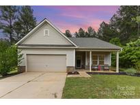 Charming single-story home with a garage and inviting front porch with craftsman-style details and manicured landscaping at 8112 Mossy Rock Rd, Waxhaw, NC 28173