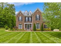 Charming brick home with manicured lawn and mature trees under a bright sky at 10012 Royal Colony Dr, Waxhaw, NC 28173
