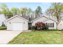 Charming one-story home featuring a garage, landscaped front yard, and manicured lawn at 12628 Waterfall Pl, Charlotte, NC 28278