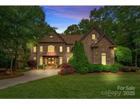 Elegant stone-front home with manicured lawn and mature trees, showcasing curb appeal and architectural details at 1305 Anniston Pl, Wesley Chapel, NC 28079