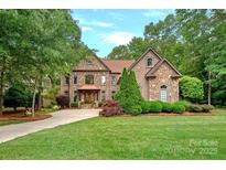 Charming stone-clad home featuring a lush green lawn, manicured landscaping, and a welcoming front entrance at 1305 Anniston Pl, Wesley Chapel, NC 28079