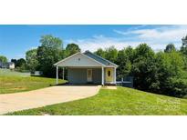 Charming single-story house with a welcoming yellow door, carport, and lush green lawn at 301 Walkers Ridge Dr, Shelby, NC 28152