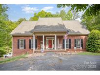Charming brick home featuring a cozy front porch with rocking chairs and a red front door at 8300 Loma Linda Ln, Waxhaw, NC 28173