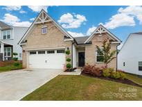 Charming brick home with a well-manicured lawn and a two-car garage with an inviting entrance and beautiful landscaping at 1024 Scotch Meadows Loop # 32, Monroe, NC 28110