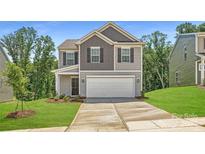 Two-story home featuring a two-car garage, landscaped front yard, and classic architectural details at 134 Dorian Pl, Troutman, NC 28166