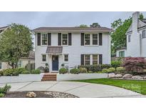 Charming white brick home with a blue door, black shutters, and manicured landscaping at 2246 Sharon Rd, Charlotte, NC 28207