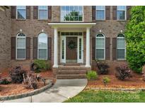 Charming brick home featuring a welcoming front entrance with a wreath, decorative shrubs, and manicured landscaping at 1116 Crooked River Dr, Waxhaw, NC 28173