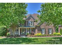 Traditional two-story brick home with a welcoming front porch and well-manicured landscaping at 16430 New Providence Ln, Charlotte, NC 28277