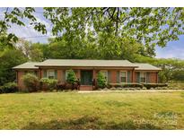 Charming brick ranch-style home with a metal roof, green shutters, and a well-maintained front yard at 3012 Morgan Mill Rd, Monroe, NC 28110