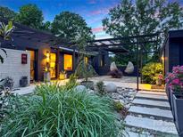 Beautifully landscaped front yard with lush greenery, stone accents, and a modern pergola at twilight at 6508 Trenton Pl, Charlotte, NC 28226